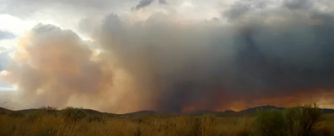 Wildfire in a open field with lots of smoke
